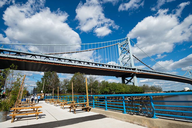 A bridge with people sitting on it and bicycles parked in the background.