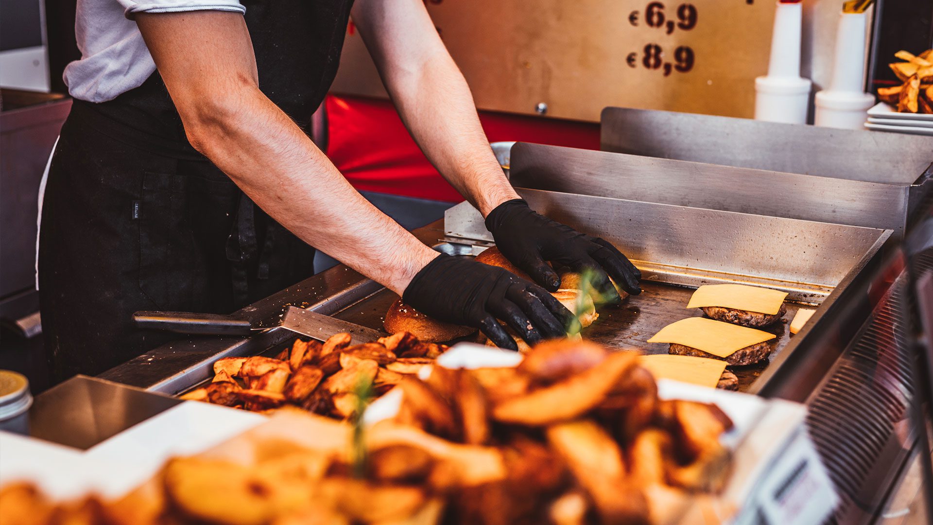 A person wearing black gloves and preparing food.